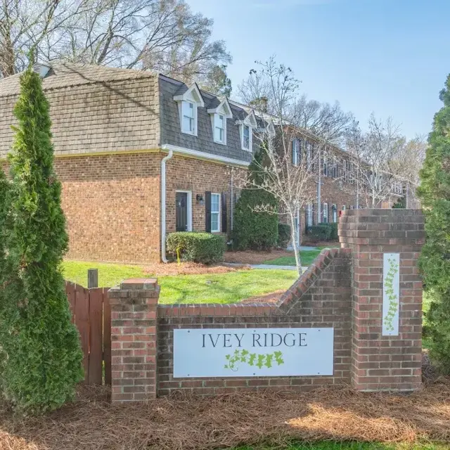 Sign for Ivey Ridge apartment community with brick structure and greenery.