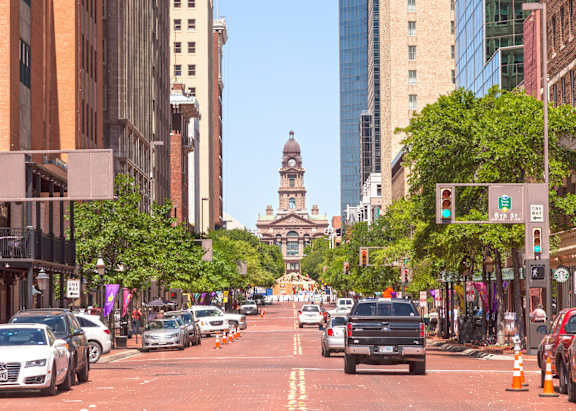 A city street with cars and buildings on either side.