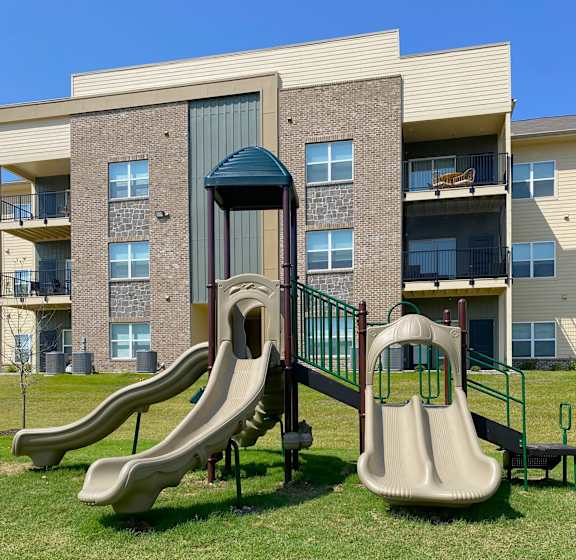 A playground with a slide in front of apartment buildings.