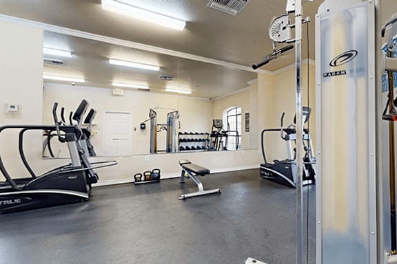 A gym with a variety of equipment including treadmills, weights, and exercise machines.