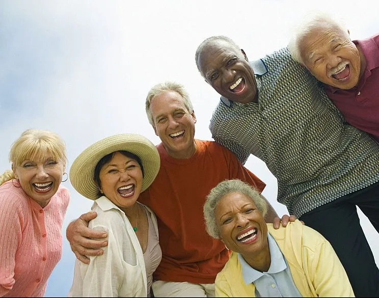 Joyful group of diverse, smiling friends enjoying a sunny outdoor gathering, exuding happiness and togetherness.