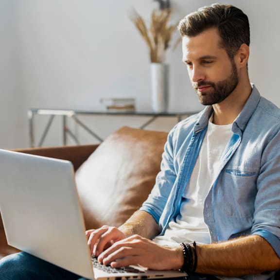 Man Sitting on Couch and Working on Laptop