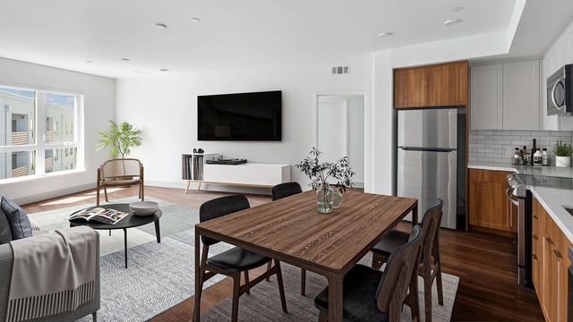 Modern living room and kitchen with dining area, stainless steel appliances, and large windows.