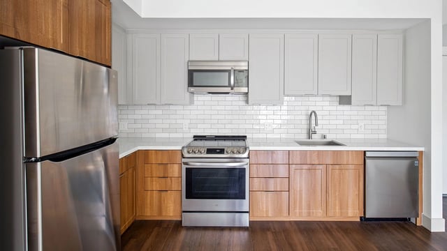 Modern kitchen with stainless steel appliances, white subway tile backsplash, and wood cabinetry.