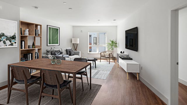 Modern living and dining area with a large table, sofa, and entertainment center.