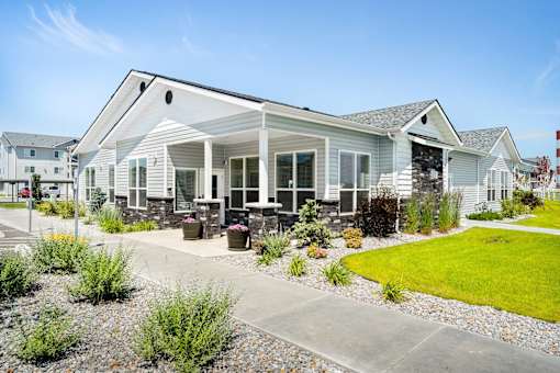 A white house with a grey roof and a small garden in front.