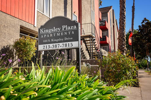 a sign for kingsley plaza apartments in front of a building