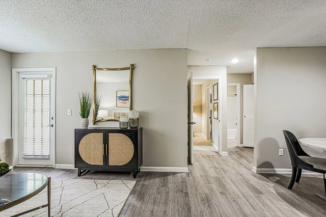 Stylish living area with a decorative cabinet and mirror, leading to a hallway.