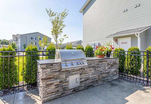 A stone wall with a grill on top and a fence in front.