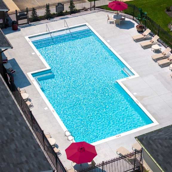 A large outdoor swimming pool surrounded by lounge chairs and umbrellas.