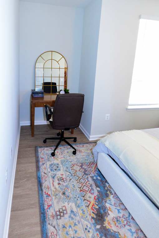 A room with a desk, chair, and rug.