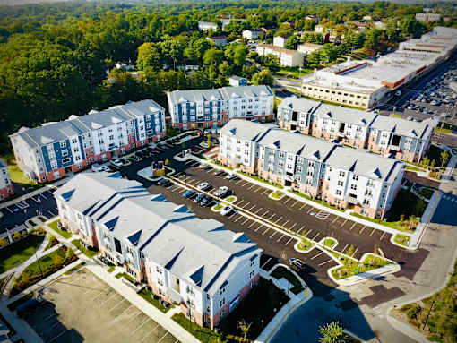 Apartment complex with a parking lot in front.