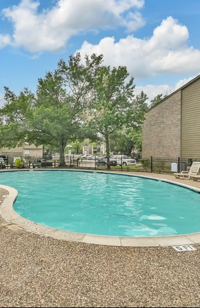 Inviting outdoor swimming pool surrounded by lush greenery and modern lounge chairs, perfect for relaxation.