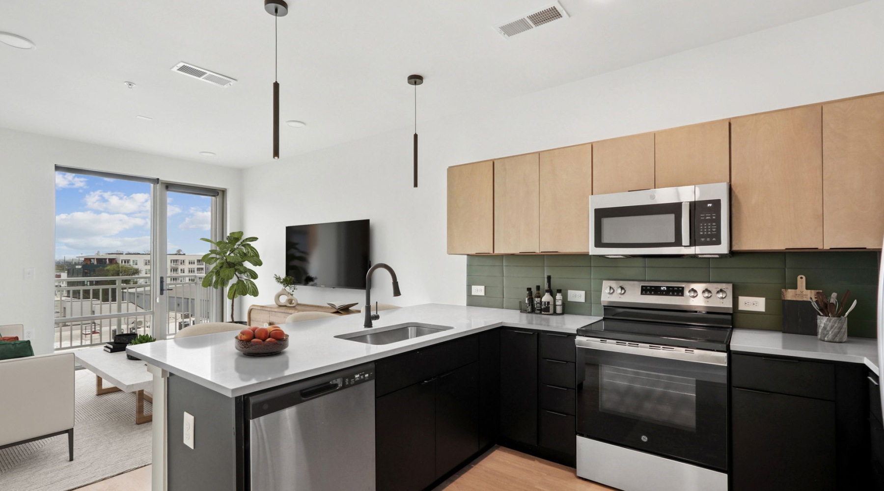 The kitchen of an apartment at Westerly House in Nashville, complete with quartz countertops, stainless steel kitchen appliances, and a large window and door to a balcony.