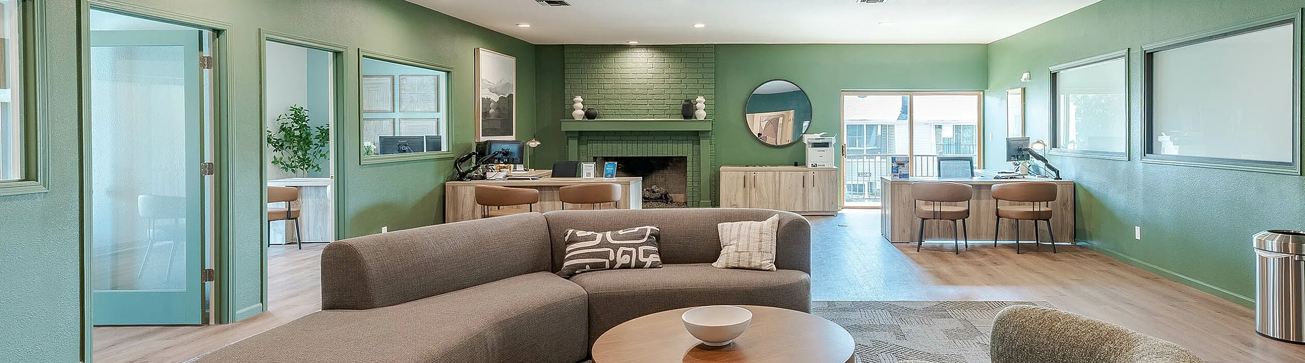 Modern lounge area with vibrant green walls, stylish curved sofa, and contemporary decor, perfect for relaxation and gatherings.