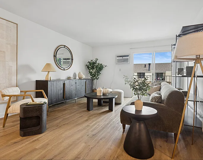 Elegant living room with modern decor, featuring a large window with natural light, chic furniture, and stylish accents.