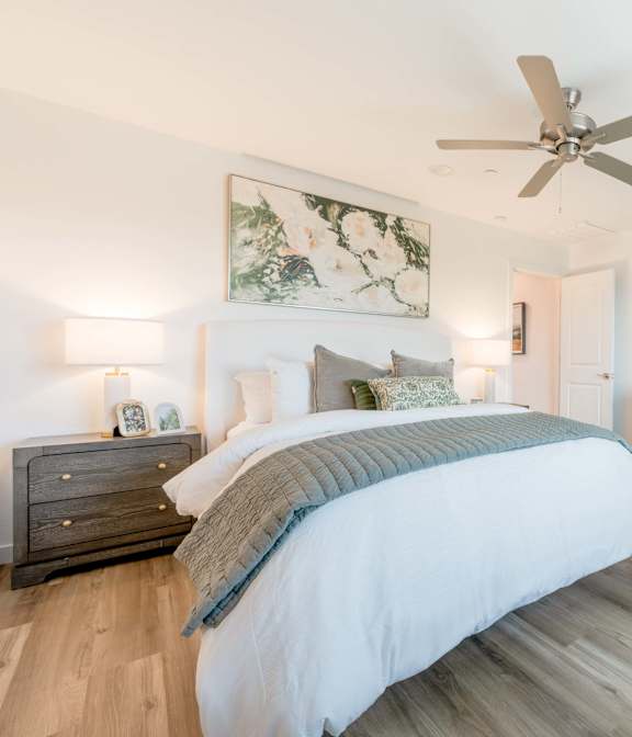 A bedroom with a large bed, a dresser, and a ceiling fan.