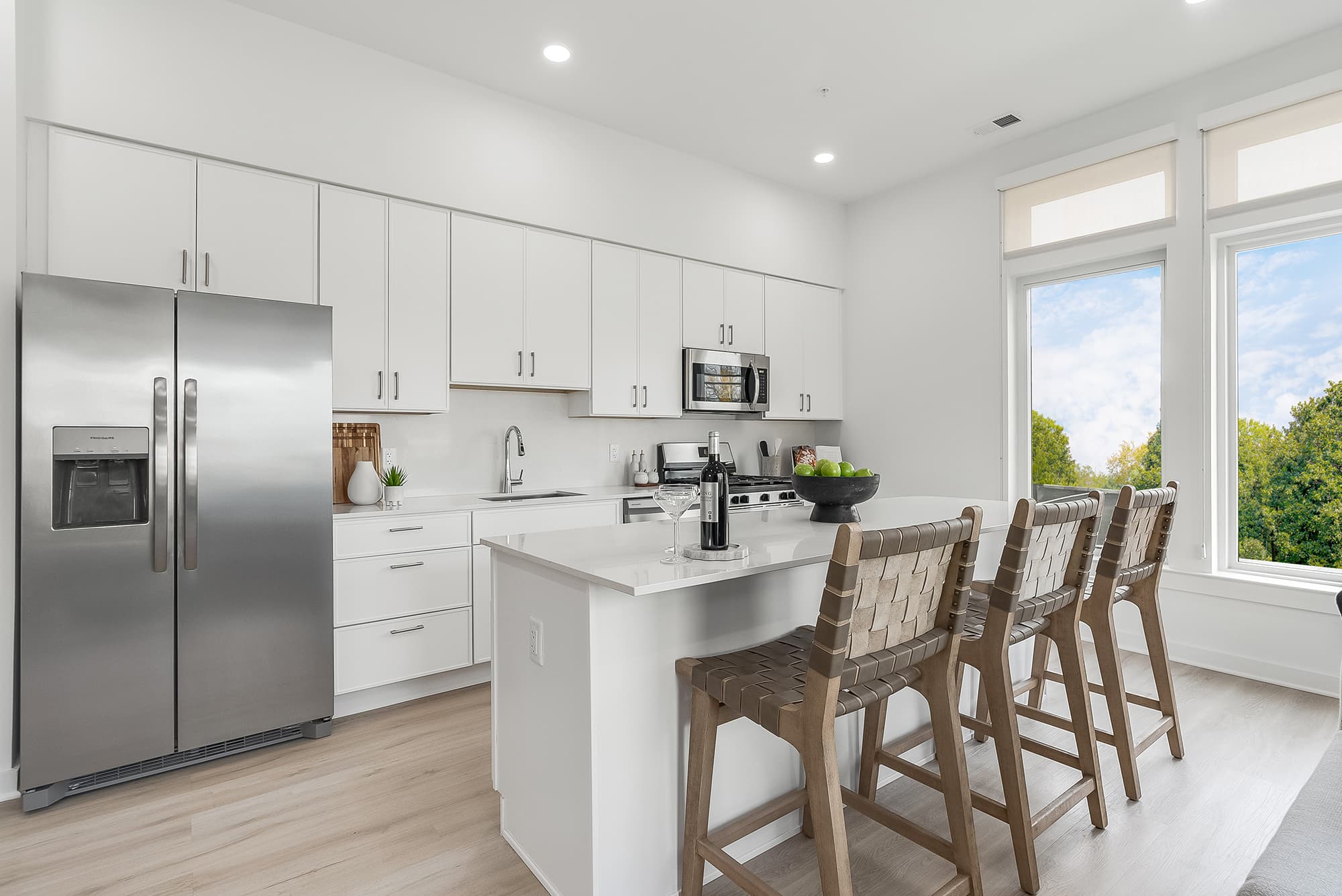 Modern white kitchen at Livana Fair Lawn in NJ featuring stainless-steel appliances and large island seating.