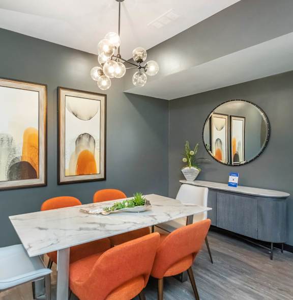 A dining room with a white table and orange chairs at Crest at East Cobb Apartments, Marietta