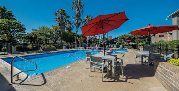 A pool with red umbrellas and chairs.