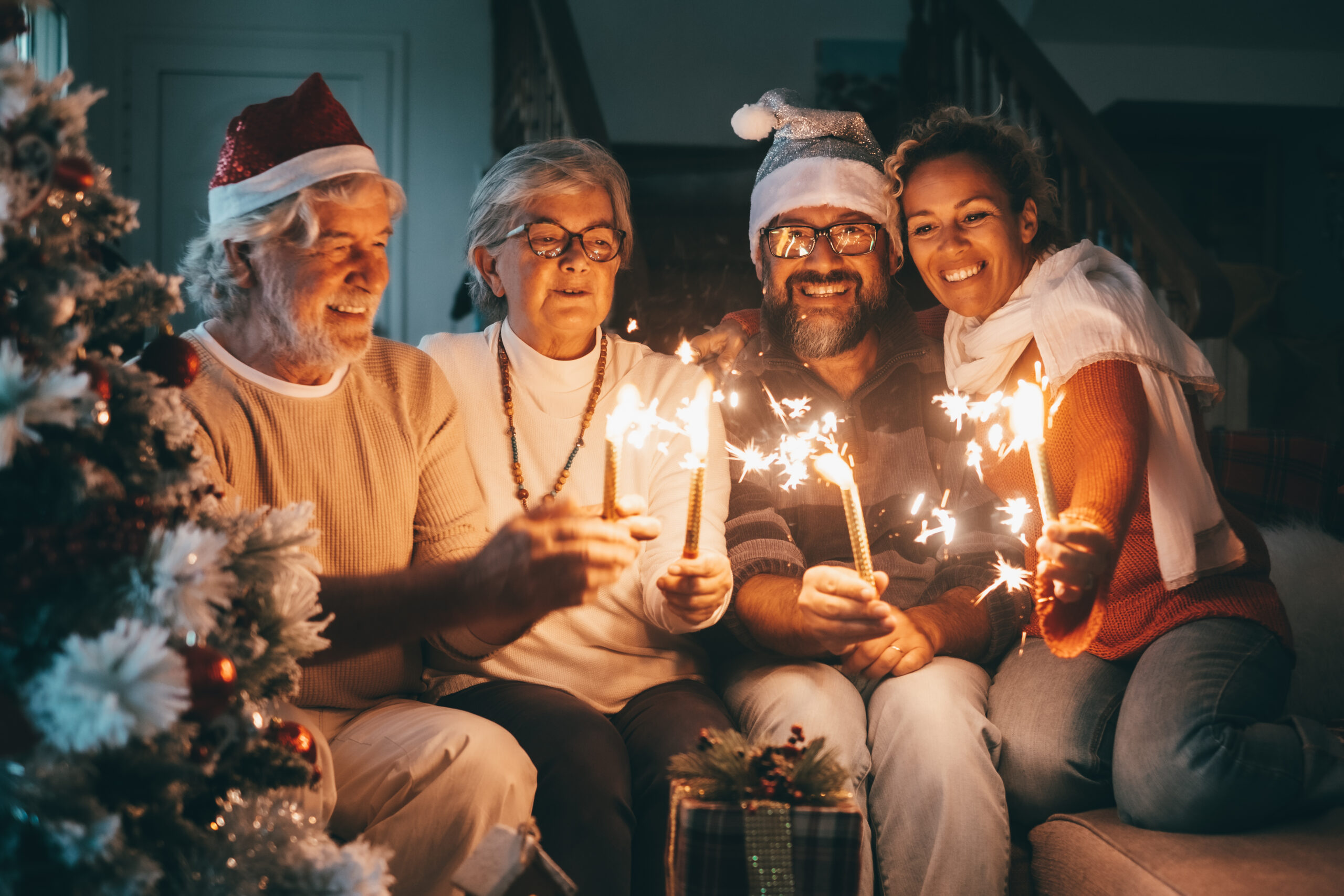 A group of smiling seniors holding sparklers and wearing Santa hats