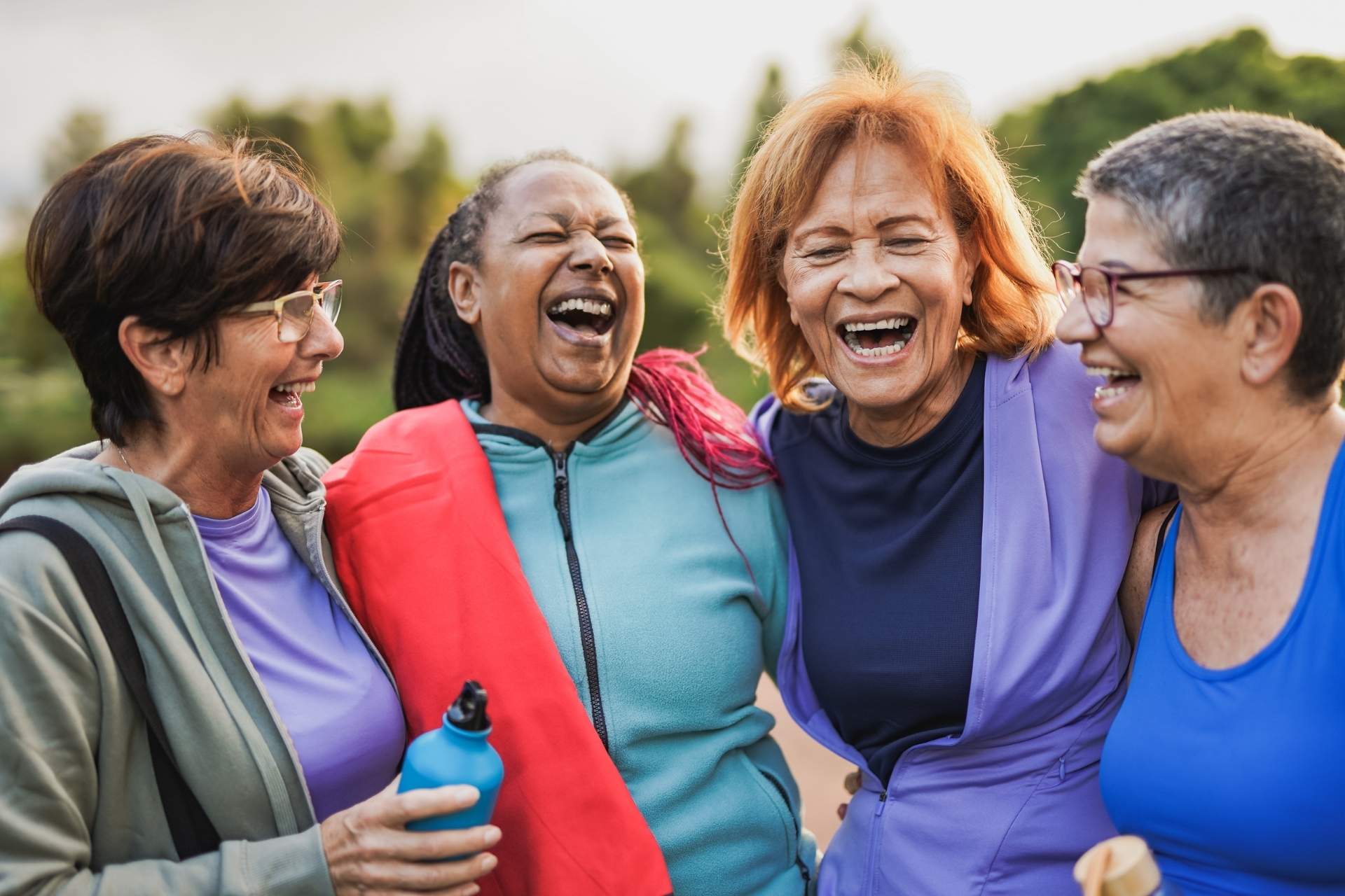 A group of senior women laughing together in workout clothes.