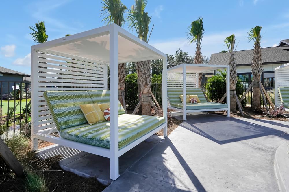 A white outdoor daybed with a green cushion is in the foreground.