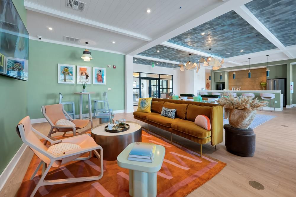 A living room with a yellow couch and a glass table.
