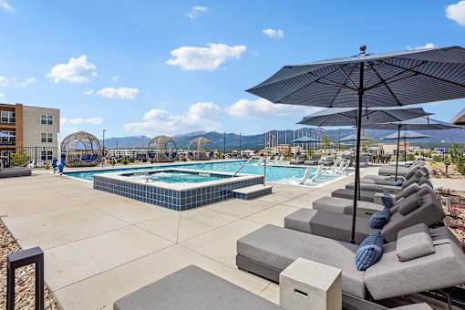 A pool area with sun loungers and umbrellas.