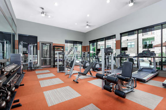 A gym with orange flooring and various exercise equipment.