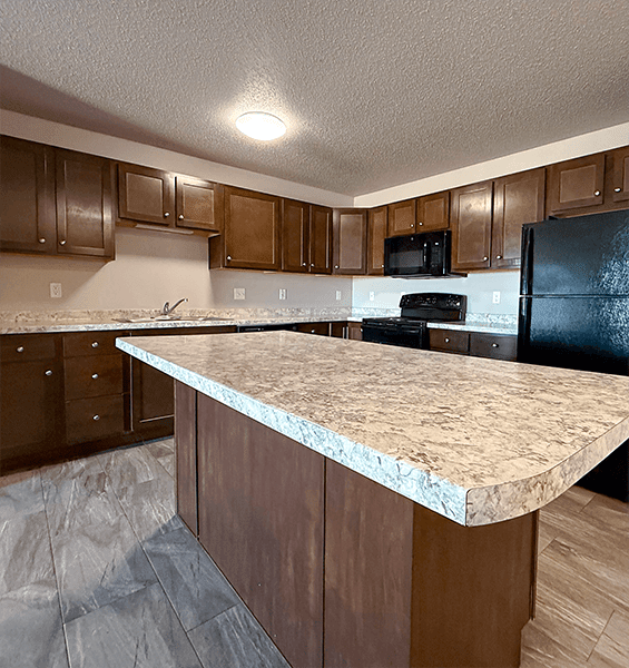A kitchen with a granite counter top and wooden cabinets.