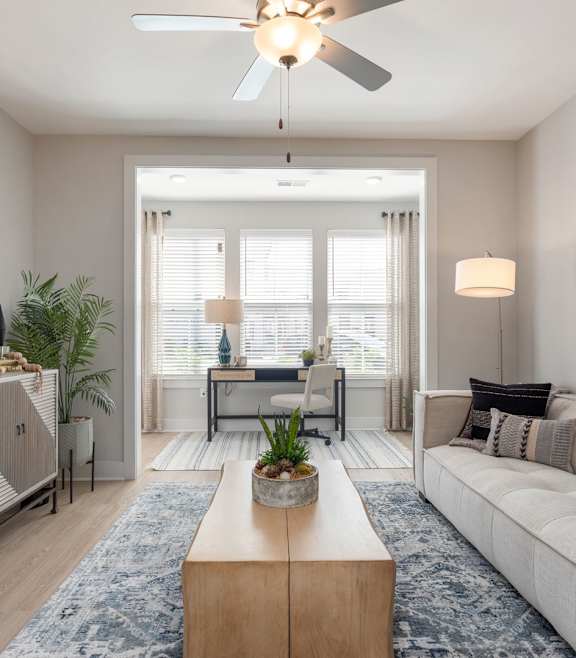 A modern living room with a blue couch and a coffee table. at Bristol at New Riverside Apartments, Bluffton, SC, 29910