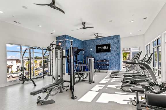 A gym with a row of treadmills and a blue wall with the word