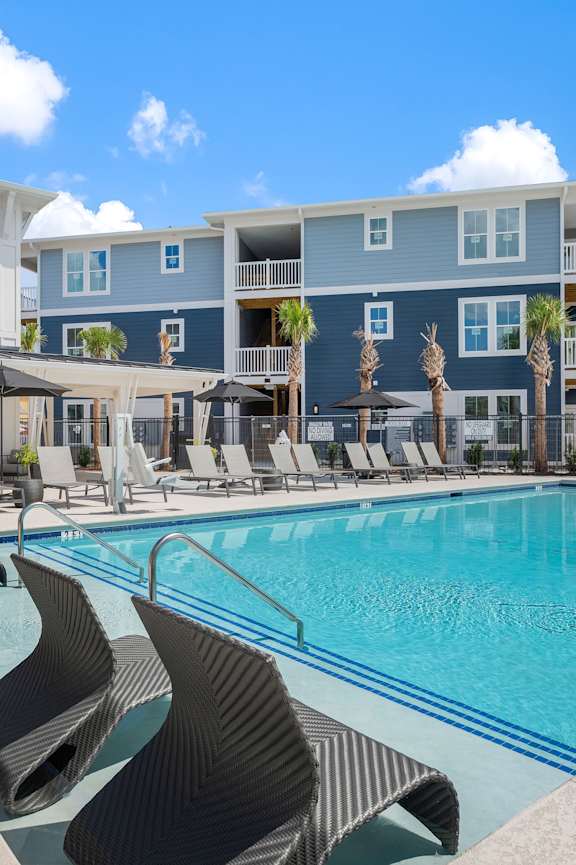 a pug sitting in a blue chair in a living room at Bristol at New Riverside Apartments, Bluffton, SC, 29910