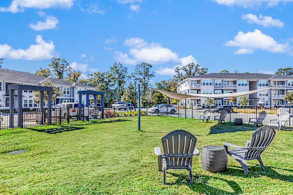Two chairs and a table are on a lawn in front of a building.