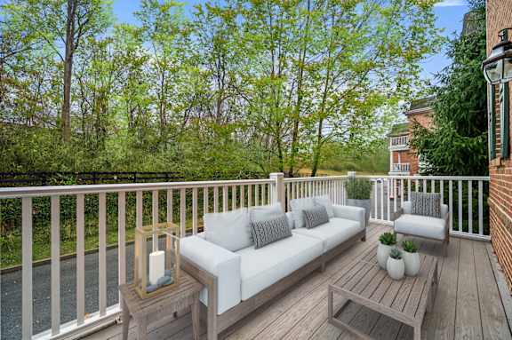 A wooden deck with a white couch and pillows.
