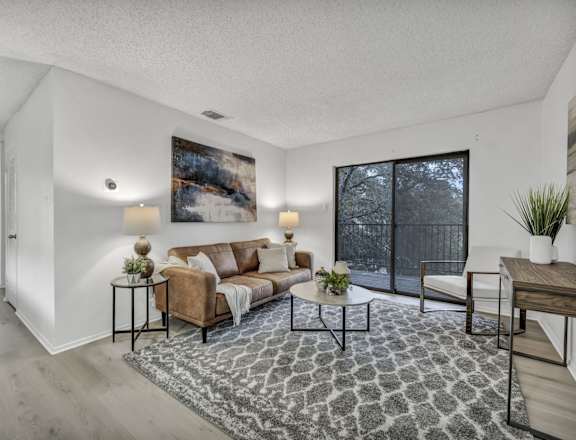 A living room with a couch, a chair, a coffee table, and a rug.