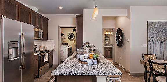 A kitchen with a granite counter top and stainless steel appliances.