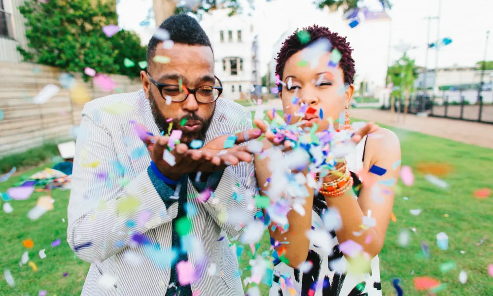 man and woman blowing confetti at camera