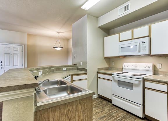 A kitchen with white appliances and a sink in Arlington, TX.
