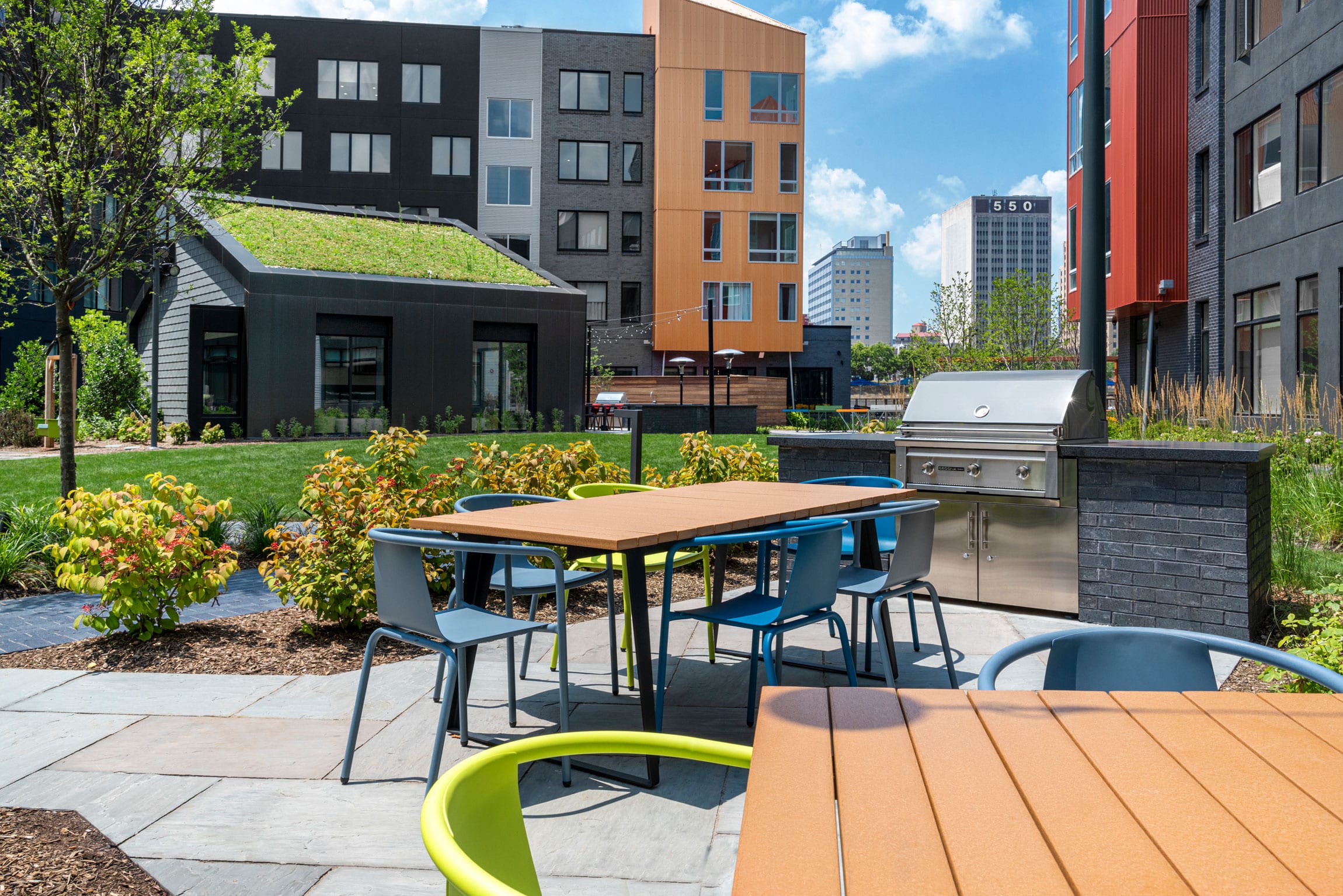 dining tables, colorful green and blue chairs and grill in apartment bbq area