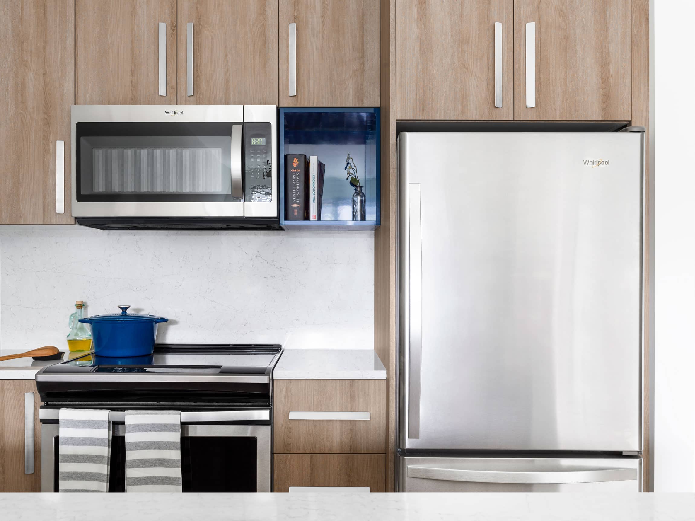 modern apartment kitchen with light brown cabinets and stainless steel appliances
