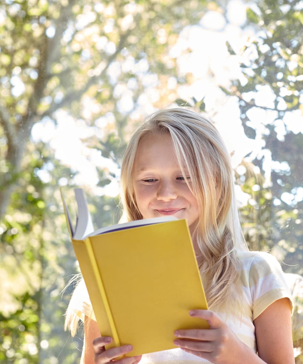Child reading a book on a very nice day at the park near Greenwood Plaza in Centennial, Colorado