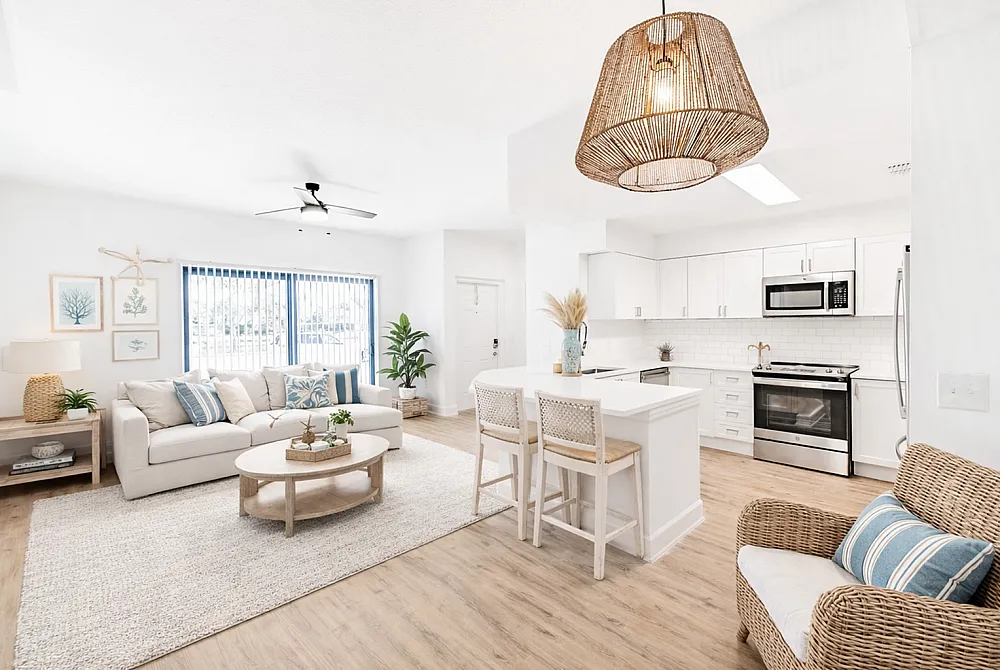 Bright and airy open-concept living room and kitchen with modern decor, light wood flooring, and stylish wicker furnishings.