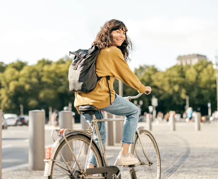 Joyful cyclist enjoying a sunny day in the city, showcasing freedom and outdoor lifestyle.