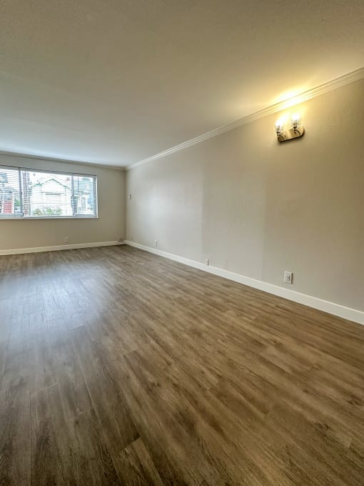 Spacious empty living room with laminate flooring at The Chase Apartments Homes, Oakland, California