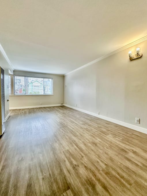 Bright living room with hardwood floors and window at The Chase Apartments Homes, Oakland