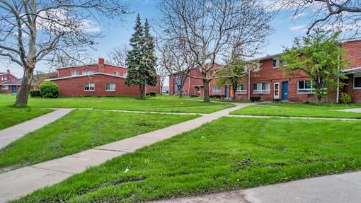 A row of red brick houses with green lawns in front.