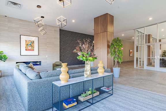 A modern living room with a grey sofa, a white coffee table, and a large painting on the wall.