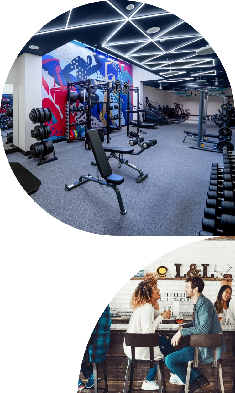 Gym at The 202 in DC with modern equipment, and a nearby bar area where two people are talking.